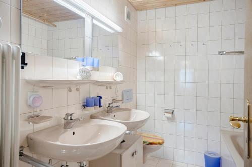 a white bathroom with two sinks and a mirror at Ferienwohnung Vogel in Wertach
