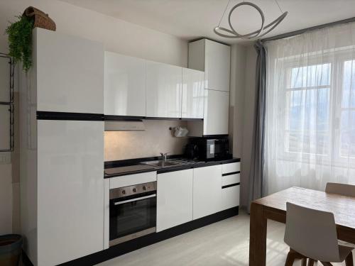 a white kitchen with white cabinets and a table at Val D'Orcia Panoramic Suite in Montalcino