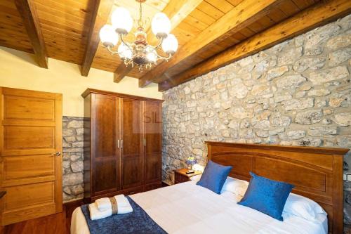 a bedroom with a bed and a stone wall at Fuente Buelna By Silastur in Buelna