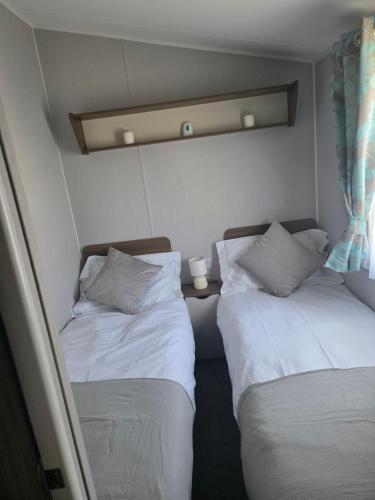 two beds in a small room with two pillows at 51 Denbigh 8 berth static caravan in Prestatyn