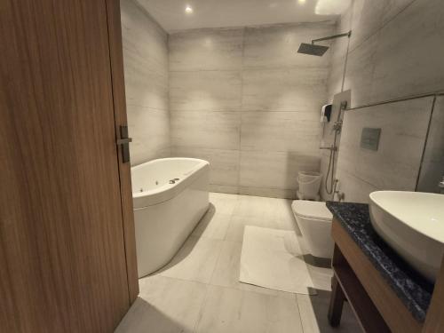 a bathroom with a tub and a sink and a toilet at Hotel Imperia Grand in Mohali