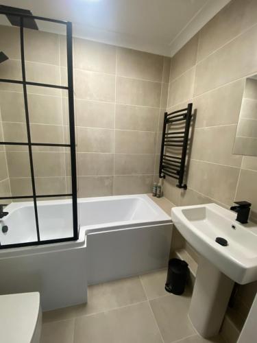 a white bathroom with a tub and a sink at Home in Greatstone in Greatstone
