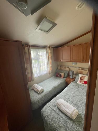 a small bedroom with two beds and a window at 38 the pines in Newton on the Moor