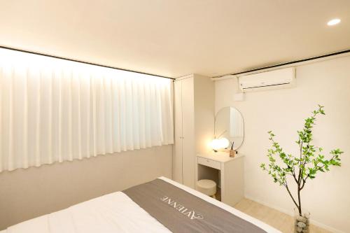 ein kleines Schlafzimmer mit einem Bett und einem Spiegel in der Unterkunft AvIENNE 홍대 명동 이태원 DDP KSPO 경북궁 롯데월드 성수 in Seoul