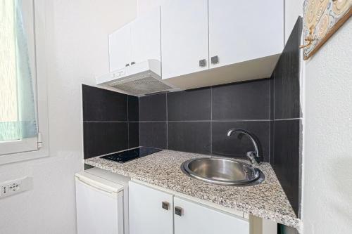 eine kleine Küche mit Spüle und schwarzen Fliesen in der Unterkunft Da Tallolo in Cagliari