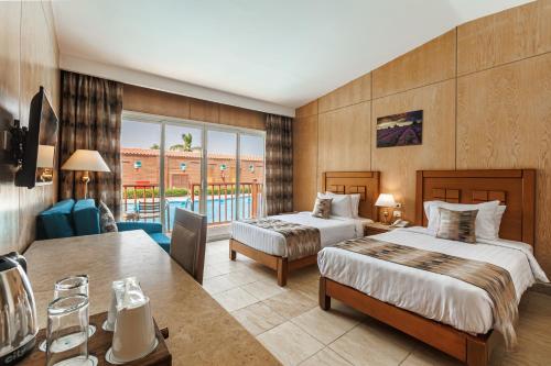 a hotel room with two beds and a desk at Sunrise Solara Aqua park Resort in Hurghada