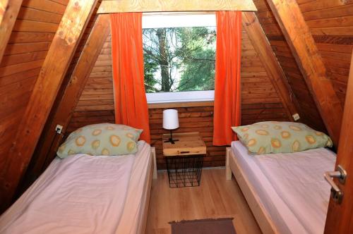 two beds in a small room with a window at Kaszuby Stężyca holiday cottage in Stężyca