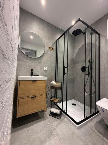 a bathroom with a shower and a sink and a mirror at Apartament Centrum in Olsztynek