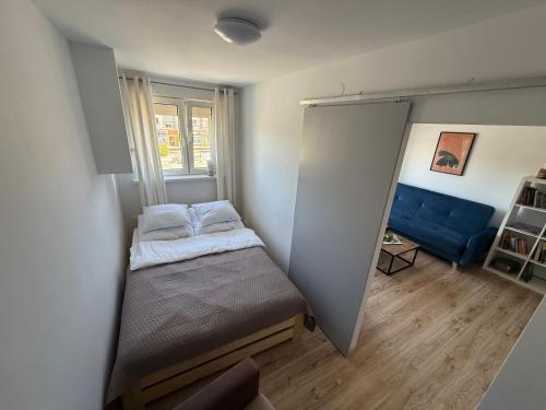 a small room with a bed and a blue couch at Apartament Centrum in Olsztynek