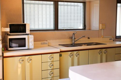 a kitchen with a microwave and a sink at Island Base Shimami in Nobeoka