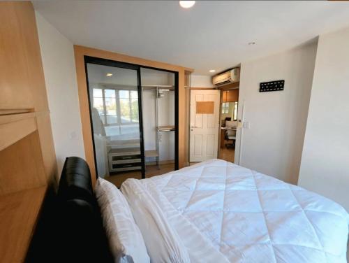 a bedroom with a large white bed in it at Cozy Minimal 1BR CMBD Pool Long Stay Friendly in Phra Khanong