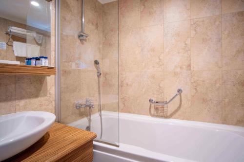 a bathroom with a shower and a tub and a sink at Blue Diamond Alya Hotel in Alanya
