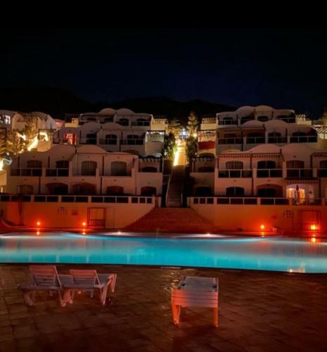 a swimming pool with two benches in front of a building at Tigert agadir in Agadir