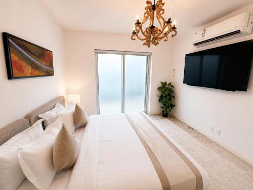 a white bedroom with a large bed and a tv at Liora Inside Al Dana beach Resort in Half Moon Bay