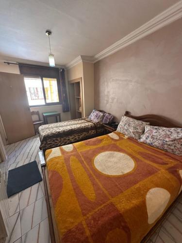 a bedroom with two beds in a room with a large blanket at Hotel Aswan in Oujda