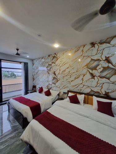two beds in a hotel room with a stone wall at Hotel Pushkar Pulse in Pushkar