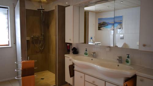 a bathroom with a sink and a shower with a mirror at Ferienwohnung Kohler - Königsfeld in Königsfeld