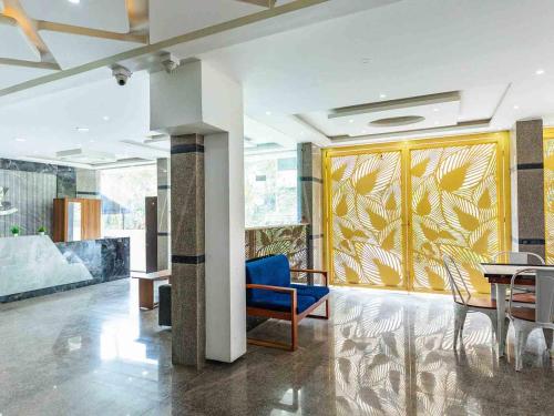 a lobby with a blue chair and a table at Z Express Aradhana in Bangalore