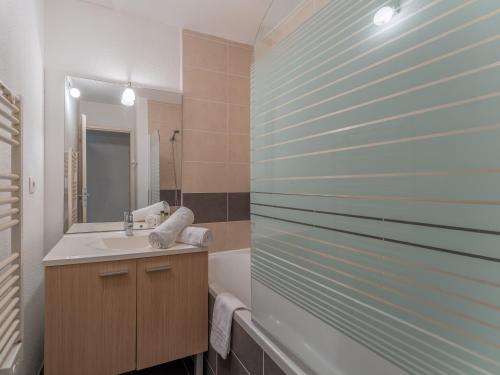 a bathroom with a sink and a tub and a mirror at Vacancéole - Les Rives du Lac in Lacanau