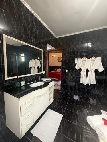a bathroom with a sink and a mirror at Pousada Bahan Suites privativas - ideal para Casais in Ubatuba