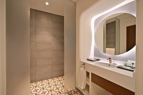 a bathroom with a sink and a mirror at Mina Hotel and Residences By The Torch in Doha