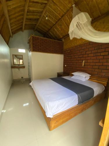 a bedroom with a large bed with a brick wall at Upus Homestay in Tetebatu
