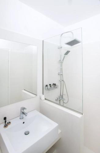 a white bathroom with a sink and a shower at Bianco Olympico Beach Resort by Anayia All Inclusive Resorts in Vatopedi