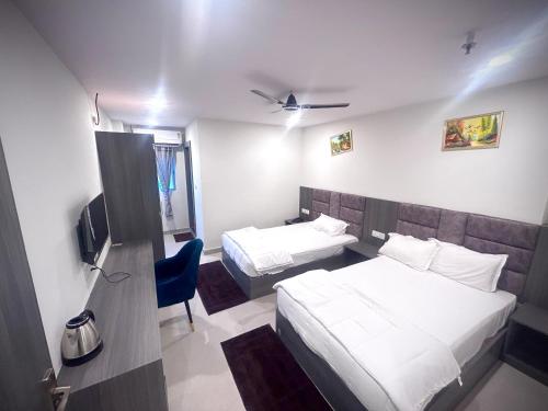 a hotel room with two beds and a tv at Hotel Vira in Cuttack
