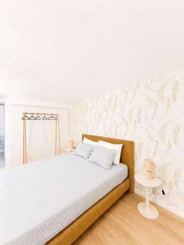 a white bedroom with a bed and a wall at Casa Trainêra in Nazaré