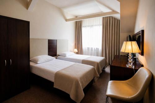 a hotel room with two beds and a chair at Agat Hotel in Łódź