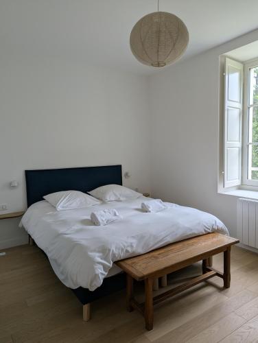 a bedroom with a bed with white sheets and a wooden bench at Chambres au vert - Proche aéroport et Nantes in Saint-Aignan-Grand-Lieu