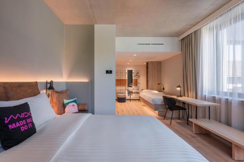 a bedroom with a large bed with a desk and a bed sidx sidx at Moxy Budapest Downtown in Budapest
