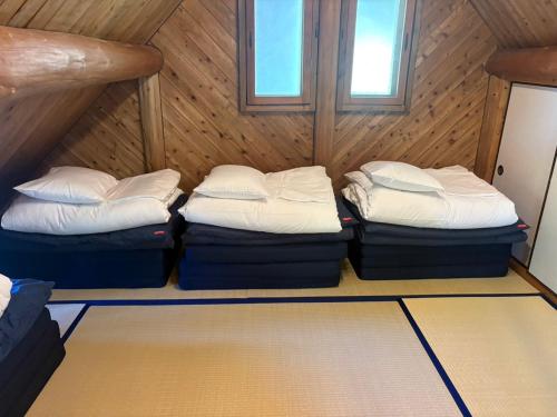 a room with three bunk beds in a cabin at Lodge Kurokawa 1 in Minamioguni