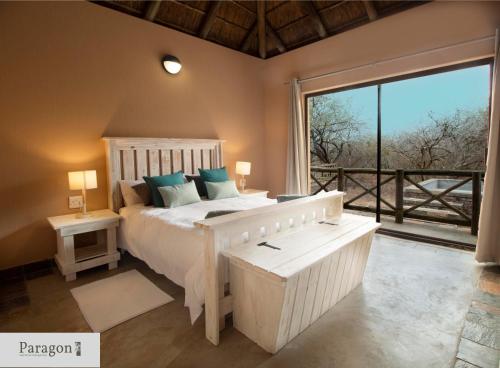 a bedroom with a white bed and a large window at Majolie, Private Pool, Look Out Tower in Marloth Park