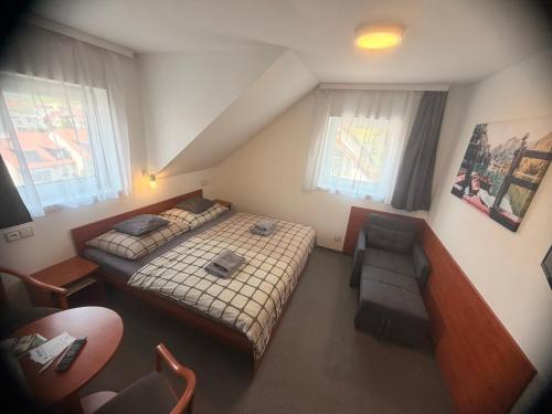 a small bedroom with a bed and a chair at Penzion Hornička in Český Krumlov
