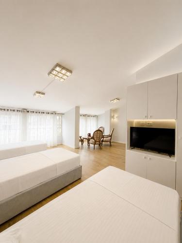 a white room with two beds and a television at Kein Hotel in Durrës