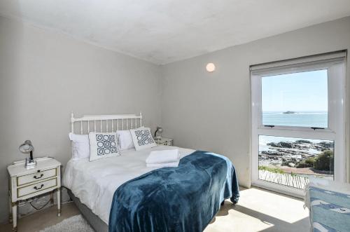 a bedroom with a bed and a window with the ocean at Voetjieshang in Yzerfontein