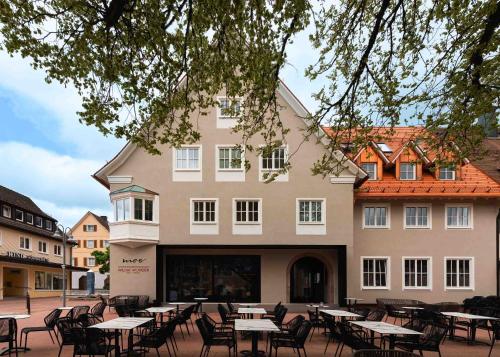 a building with tables and chairs in front of it at Moe by Limehome in Freudenstadt