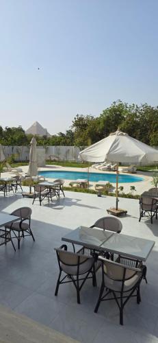 a group of tables and umbrellas next to a pool at Nakhil Pyramids Resort in Cairo