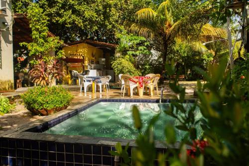 a pool with chairs and a table in a yard at Maraca Vibes Hostel in Porto De Galinhas