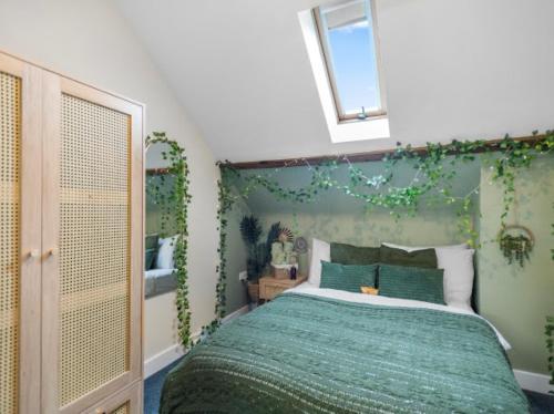 a bedroom with a green bed with a window and plants at Upbeat Jungle Loft Apartment in Derby