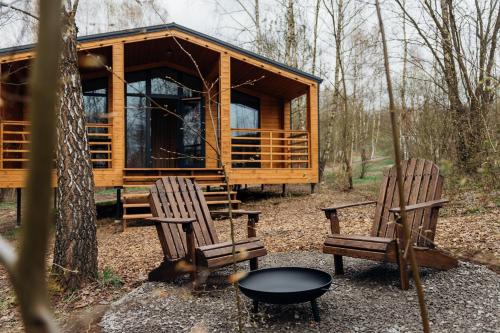a cabin in the woods with two chairs and a table at УЛІС Віняви in Derevach