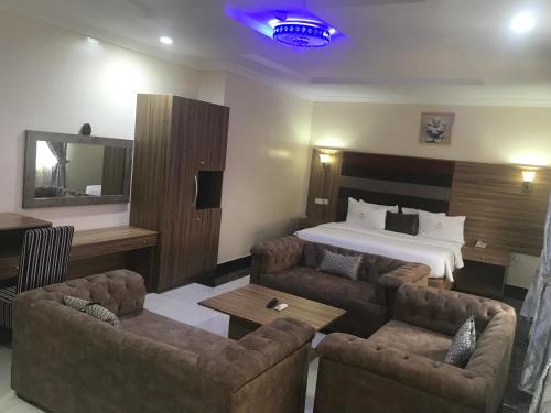 a hotel room with a bed and two couches at ADJ Royalty Hotel & Suites in Benin City