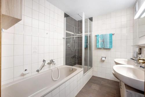 a white bathroom with a tub and a sink at Haus Grüntensee in Wertach
