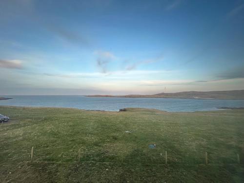 a field with a view of a body of water at Kelsingra Self Catering in Lerwick/Tingwall Airport