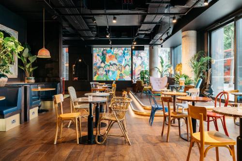 a restaurant with tables and chairs in a room at Ruby Zoe Hotel London by IHG in London