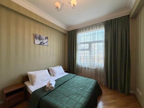 a bedroom with a green bed and a window at Mayden Tower apartment in Baku