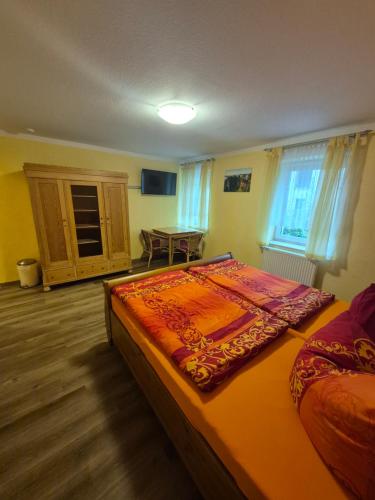 a bedroom with a bed and a table in it at Pension am Lindenbaum in Kirnitzschtal