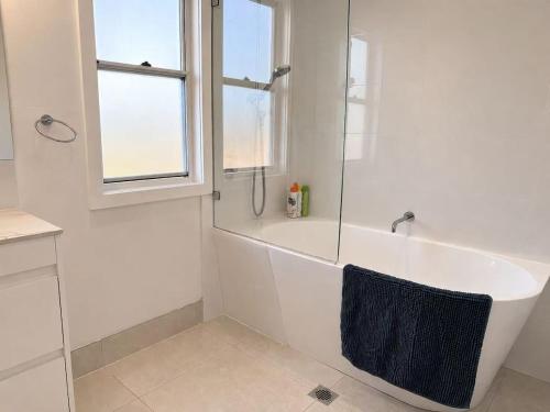 a white bathroom with a tub and a window at 22 Pimpama Home in Pimpama