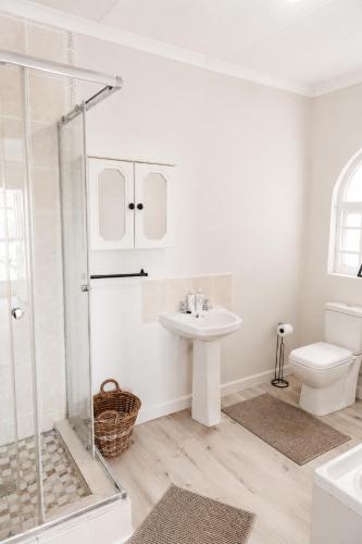 a white bathroom with a sink and a toilet at Idylla Guest Home in Kenton on Sea